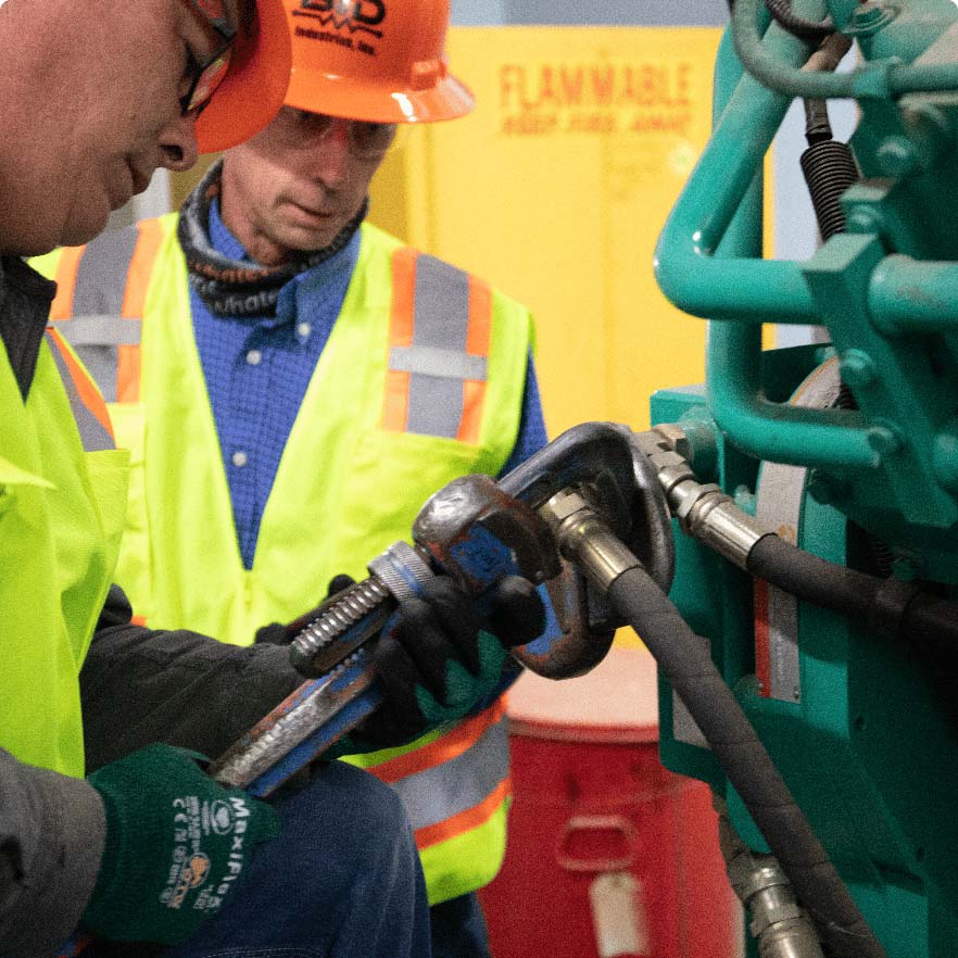 Two B&D Industries employees repairing industrial equipment